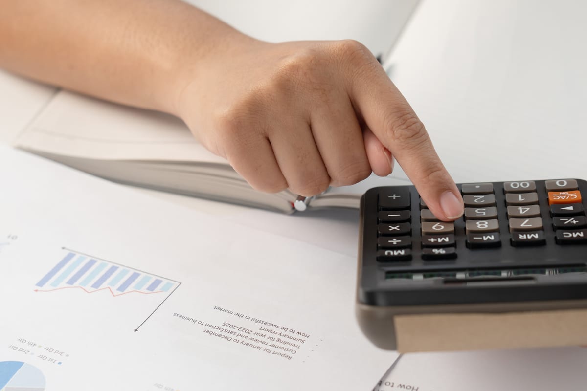mastering the business side of estheticis - woman with calculator at desk